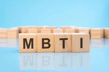 Mavi arka planda ahşap küplerde MBTI kelimesi. İş konsepti maaş ya da yapılan iş için ödeme. MBTI - Myers-Briggs Tip Göstergesinin kısaltması