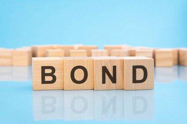 Mavi arka planda tahta küplerle ilgili kelime BOND. Yapılan iş için maaş ya da ödeme konsepti.