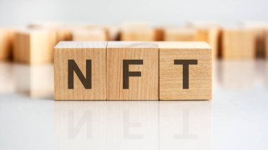 Gri arkaplandaki tahta küplere NFT konsepti. Finansal, ticari ya da ekonomik temalı bir yazı. NFT - Parasız Jeton 'un kısaltılmışı