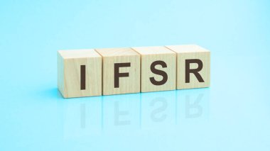 ifsr- harfli ahşap blokların kısaltması. Tablonun aynalı yüzeyindeki başlığın yansıması. Seçici odaklanma. ifSR - sigorta finansal güç derecelendirmesinin kısaltılmışı