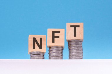 Nft - tahta küpler üzerine yazı, bozuk paralar, mavi arka plan, iş konsepti. nft - çiftlik harici maaşların kısaltılmışı