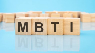 Mavi arka planda ahşap küplerde MBTI kelimesi. Küplerdeki yazılar yüzeyden yansıyor. İş konsepti. MBTI - Myers-Briggs Tip Göstergesinin kısaltması