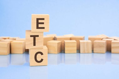 Parlak soluk bir leylak ve mavi arka planda, açık tahta bloklar ve ETC yazılı küpler. Küpler yüzeyden yansıyor. ETC - elektronik ticaret doğrulaması veya benzeri şeylerin kısaltması