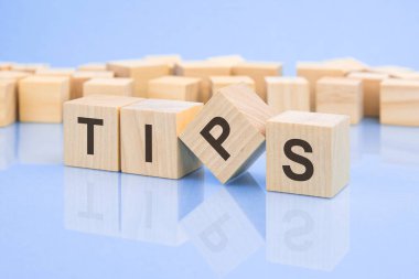 Soluk bir leylak masasının parlak yüzeyinde TIPS harfleri olan dört tahta blok. Küplerdeki yazıt yüzeyden yansıyor..