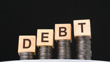 Siyah arka planda madeni paralar ve yazılı tahtadan küpler var.