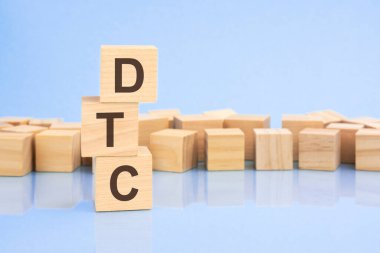 Parlak soluk bir leylak ve mavi arka planda, açık tahta bloklar ve DTC yazılı küpler. Küpler yüzeyden yansıyor. DTC - Doğrudan Tüketiciye 'nin kısaltması