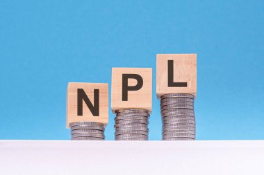 NPL - ahşap bloklar üzerine yazı, bozuk paralar, mavi arka plan, iş konsepti. npl - Yapılmayan Kredilerin kısaltılmışı
