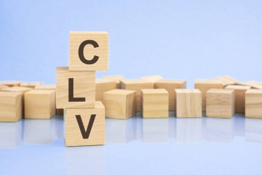 parlak soluk bir leylak ve mavi arka planda, açık tahta bloklar ve CLV yazılı küpler. Küpler yüzeyden yansıyor. CLV - Müşteri Yaşam Değeri