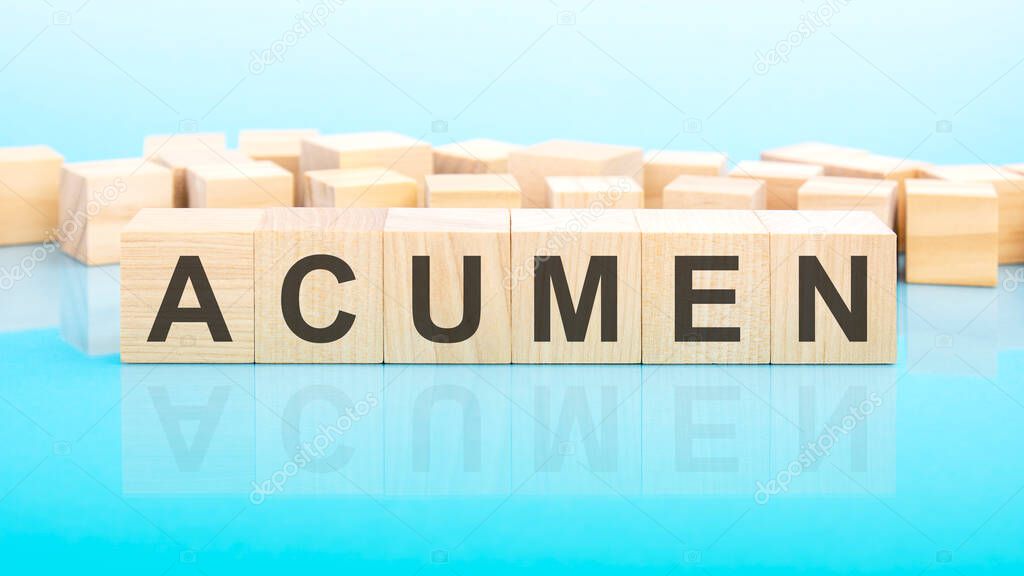word acumen made with wood building blocks. text is written in black letters and is reflected in the mirror surface of the table, blue background, business concept