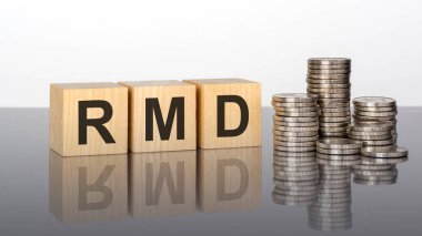 RMD - Minimum Dağıtım Gerekli 'nin kısaltması. Tahta küpler. Siyah arka planda bloklar var. Bozuk paralarla dolu desteler. Küplerdeki yazıtlar masanın yüzeyinden yansıyor. seçici odak.
