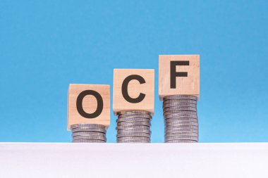 ocf - İşletim Nakit Akışı - ahşap bloklar üzerinde yazı para, mavi arkaplan, iş konsepti.