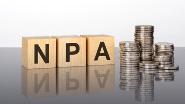 npa. wooden cubes. blocks lie on a black background. stacks with coins. inscription on the cubes is reflected from the surface of the table. selective focus. npa - Non Performing Assets clipart