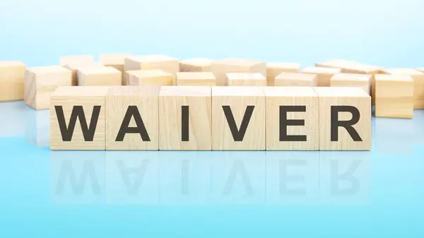 word Waiver made with wood building blocks. text is written in black letters and is reflected in the mirror surface of the table, blue background, business concept