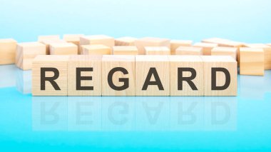 Regard, ahşap yapı taşlarından yapılmış bir kelime. Metin siyah harflerle yazılır ve masanın ayna yüzeyine yansıtılır, mavi arkaplan, iş konsepti