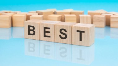 En iyi kelime tahta küplerde olur. mavi arka plan. Küplerdeki yazılar yüzeyden yansıyor. iş kavramı.