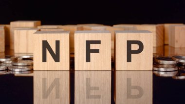 NFP - Çiftlik Dışı Maaşlar 'ın kısaltması. Bozuk paralar, siyah arka plan ve iş konsepti içeren tahta küplerle ilgili yazı. Küplerdeki yazıtlar siyah tablonun yüzeyinden yansıyor. ön görünüm