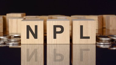 NPL - para, siyah arkaplan, iş konsepti içeren tahta küplerle ilgili metin. Küplerdeki yazıtlar siyah tablonun yüzeyinden yansıyor. Ön manzara. NPL - yerine getirilmeyen krediler