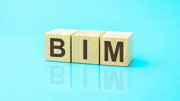 BIM - acronym from wooden blocks with letters, abbreviation BIM Building Information Modeling concept, blue background.