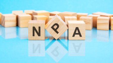 Metin npa - siyah harflerle tahta küplere yazılmış, küpler mavi cam bir yüzeye yerleştirilmiş - kavramsal sözcük küplerle şekilleniyor. npa - Performans Dışı Varlıkların kısaltması