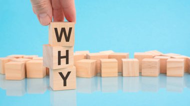 Neden mesajla ahşap küp bloğu tutan el. Küplerdeki yazılar yüzeyden yansıyor. Kopyalama alanı olan mavi arkaplan.