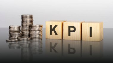 kpi. Tahta küpler. Siyah arka planda bloklar var. Bozuk paralarla dolu desteler. Küplerdeki yazıtlar masanın yüzeyinden yansıyor. kpi - anahtar performans göstergelerinin kısaltması