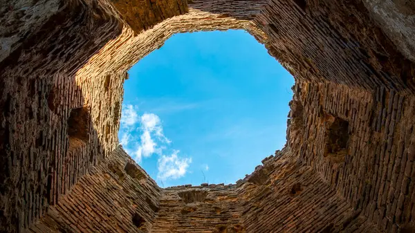 brick tower view of the clouds in the bright blue sky from below the tower, ancient ruins of a fortified fort