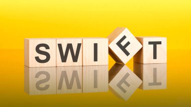 Tahta blokta hızlı bir kelime. Sarı arka plan. İş konsepti. Küplerdeki yazıtlar masanın yüzeyinden yansıyor. Swift - Uluslararası Bankalar Arası Finansal Telekomünikasyon Topluluğu