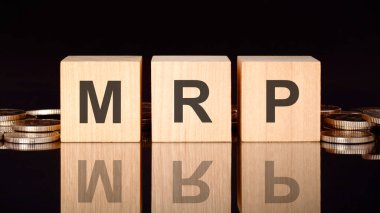 Tahta küplerle ilgili MRP metni, bozuk paralar, siyah arka plan, iş konsepti. Küplerdeki yazıtlar siyah tablonun yüzeyinden yansıyor. Ön manzara. MRP kısaltması.