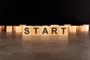 START kelimesi siyah bir arkaplanda duran tahta küplere yazılmıştır.