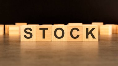STOCK kelimesi siyah arka planda duran tahta küplere yazılmıştır.