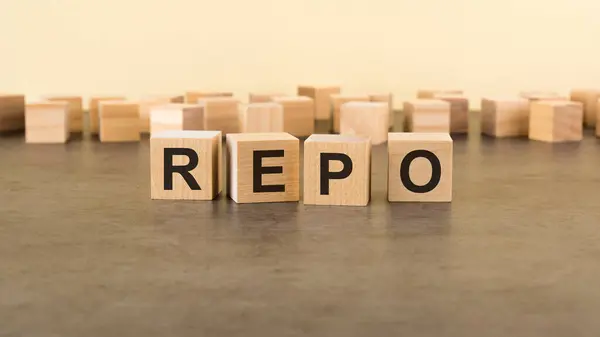 four wooden blocks with the letters REPO - on the surface table. REPO - Repurchase Agreement.