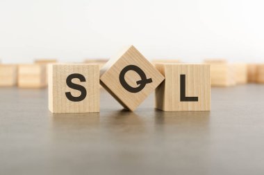 Tahta küp ve SQL sözcüğünün harfi. Gri arka planda duran tahta küpler. SQL - Yapılandırılmış Sorgu Dili 'nin kısaltması.