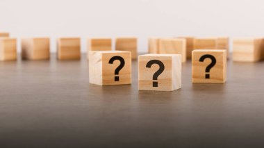 Tahta masada soru işareti olan üç tahta blok, yakın plan. Metin için boşluk. tahta arkaplan