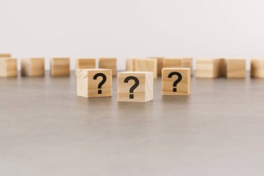 Pek çok tahta küpün önünde soru işaretleri var. Birçok soru ortaya çıkıyor. Sorun ve karışıklık. gri arkaplan.