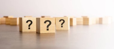 Pek çok tahta küpün önünde soru işaretleri var. Birçok soru ortaya çıkıyor. Sorun ve karışıklık. gri arkaplan.