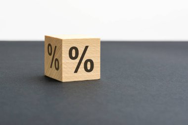 Bir tarafında yüzde işareti olan bir tahta zar, siyah arkaplanda gölge ve kopyalama alanı ile yakından görülüyor