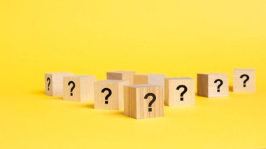 Pek çok tahta küpün önünde soru işaretleri var. Birçok soru ortaya çıkıyor. Sorun ve karışıklık. sarı arkaplan