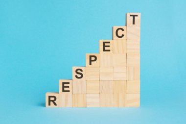 Saygı kelimesi tahta küplere yazılmıştır. Parlak mavi arkaplandaki bloklar. Şirket hiyerarşisi ve çok katlı pazarlama. Seçici odak.