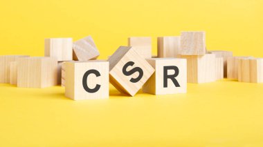 Tahta bloklar, sarı arka planda CSR yazılı. CSR - kurumsal sosyal sorumluluğun kısaltması