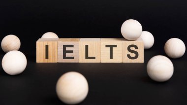 İş ve ekonomi kavramı. Siyah bir yüzey üzerinde ve üzerinde IELTS yazılı tahta küpler - Uluslararası İngilizce Dil Test Sistemi
