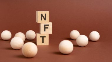 NFT-Funable Token yazılı ahşap küp piramidi, kahverengi arka planda tahta toplar.