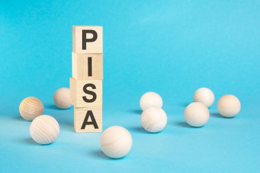 PISA ve ahşap topların olduğu ahşap küplerden oluşan bir piramit. Parlak mavi arkaplanda, sağ tarafta kopyalama alanı var.