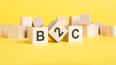 Kısaltma B2C- Tüketiciye İş. Sarı arka planda harfleri olan tahta küpler. iş konsepti resmi.