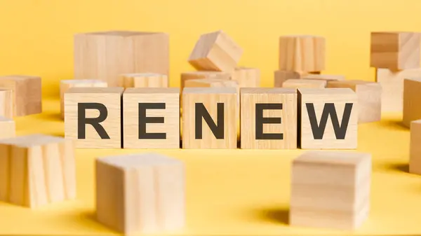 the word renew written on wooden cubes on yellow background. asset management or financial accounting concept