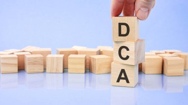 Metin DCA parlak mavi bir yüzeydeki tahta küplere yazılmıştır. İş konsepti. DCA - ortalama maliyet ortalamasının kısaltması