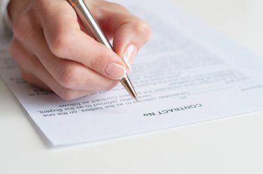 Ön plandaki kağıda bir şeyler yazan bir insan elinin yakın çekimi..