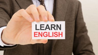 Üzerinde Learn Inglish yazan bir kart tutan işadamı.