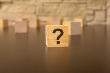 Soru işaretli doğal tahta küp, gri arkaplan.