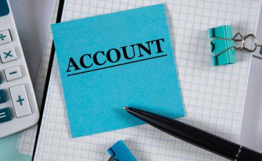 Muhasebe defteri, hesap makinesi ve kalemin arka planına karşılık mavi bir kağıt parçasına yazılmış bir kelime. İş ve finans kavramı