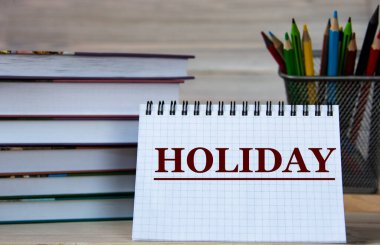 Holiday - kitapların ve kalemlerin arka planına karşı bir defter içinde kelime. Eğitim kavramı